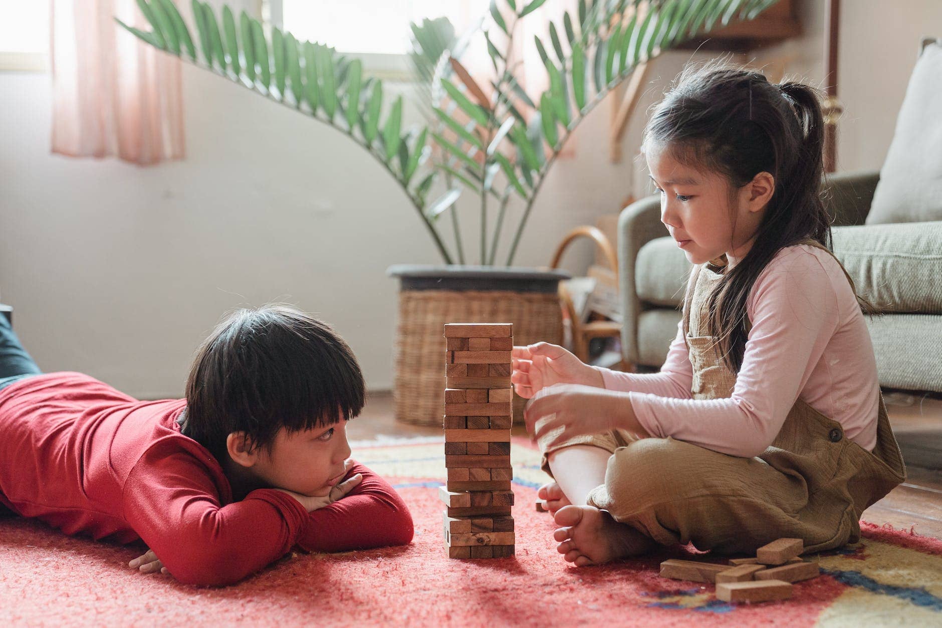 content asian children building wooden tower on floor at home